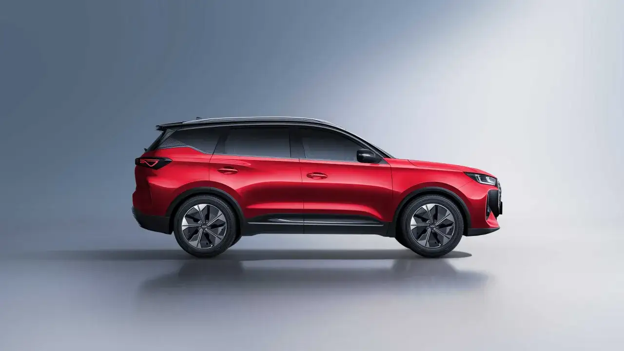 Czerwony Chery Tiggo w profilu, z czarnym dachem i przyciemnianymi szybami. Nowoczesny design SUV-a podkreślają eleganckie felgi i ostre linie nadwozia.