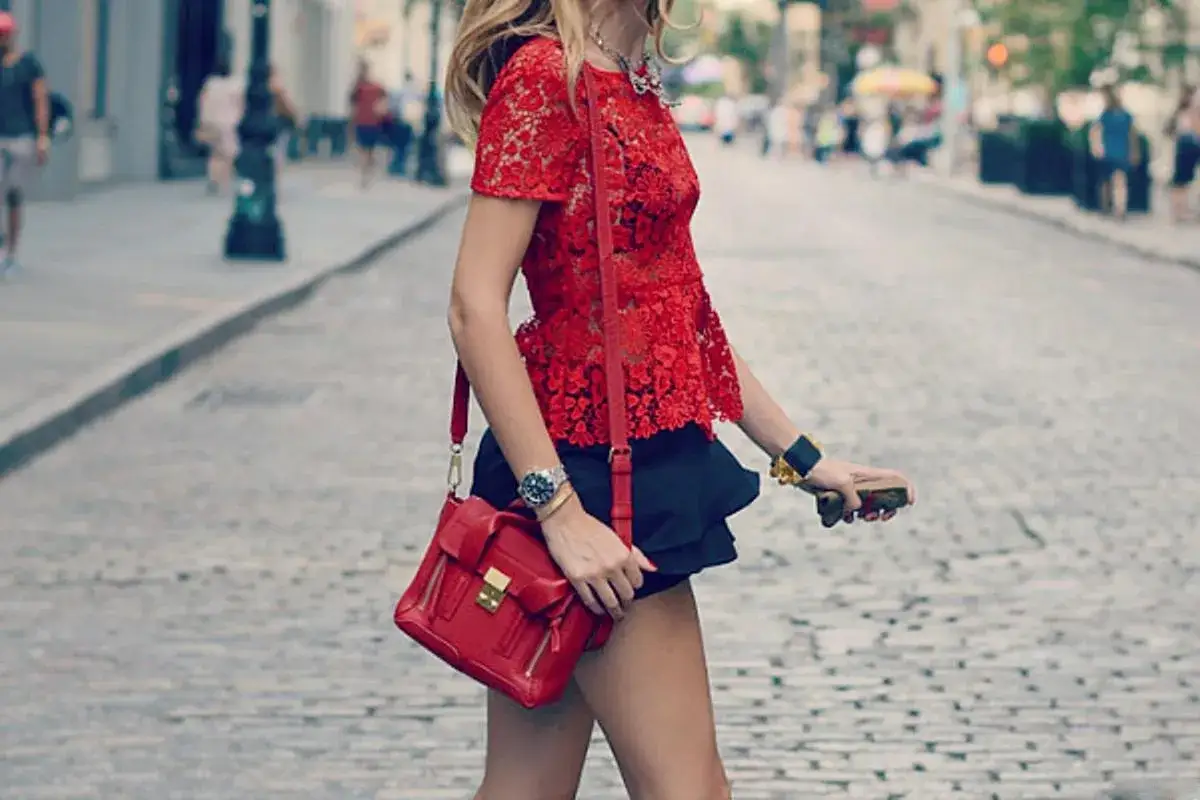 Donna con top rosso pizzo e borsa rossa, un'idea su come abbinare una borsa rossa per un look audace.
