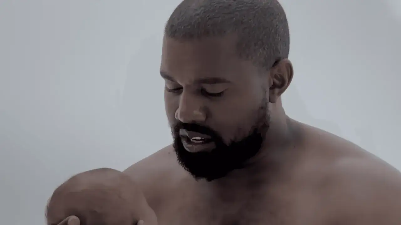 Kanye West zagina, trzymając dziecko.