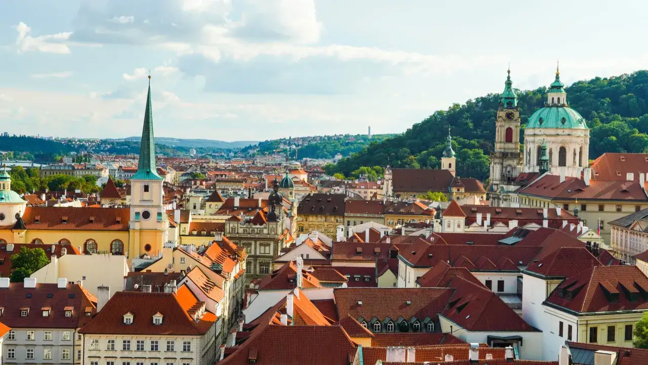Dachlandschaft von Mala Strana Prag mit Kircht&uuml;rmen und gr&uuml;nen Kuppeln unter blauem Himmel.