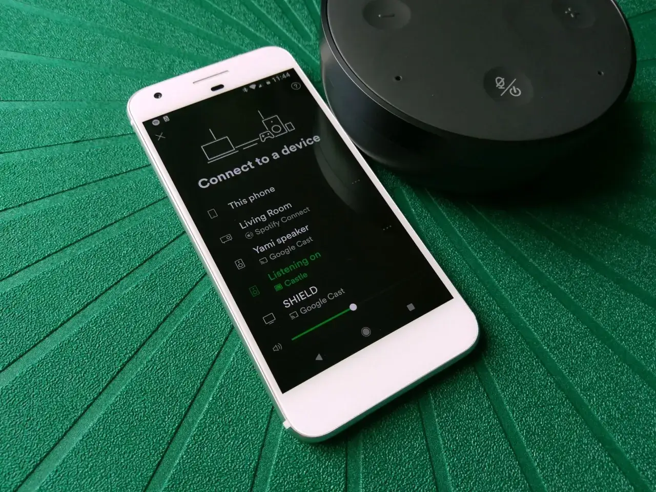 Telefon z aplikacją Spotify Connect do wyboru urządzeń. Obok widoczny głośnik.