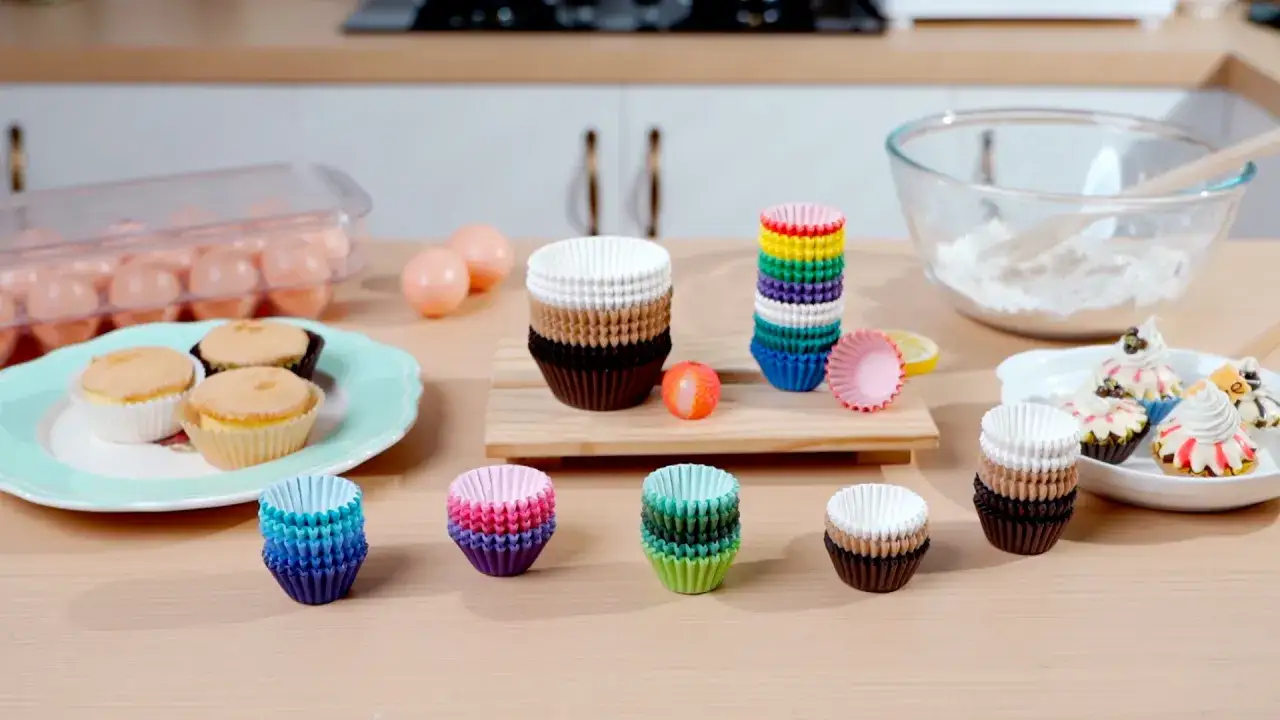 Färgglada cupcake formar i olika storlekar och färger ligger utspridda på ett träbord, redo för bakning.