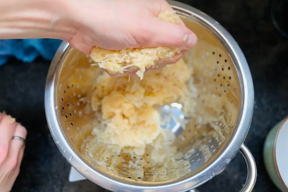 Hand presst Sauerkraut für ein Krautkrapfen Rezept aus.