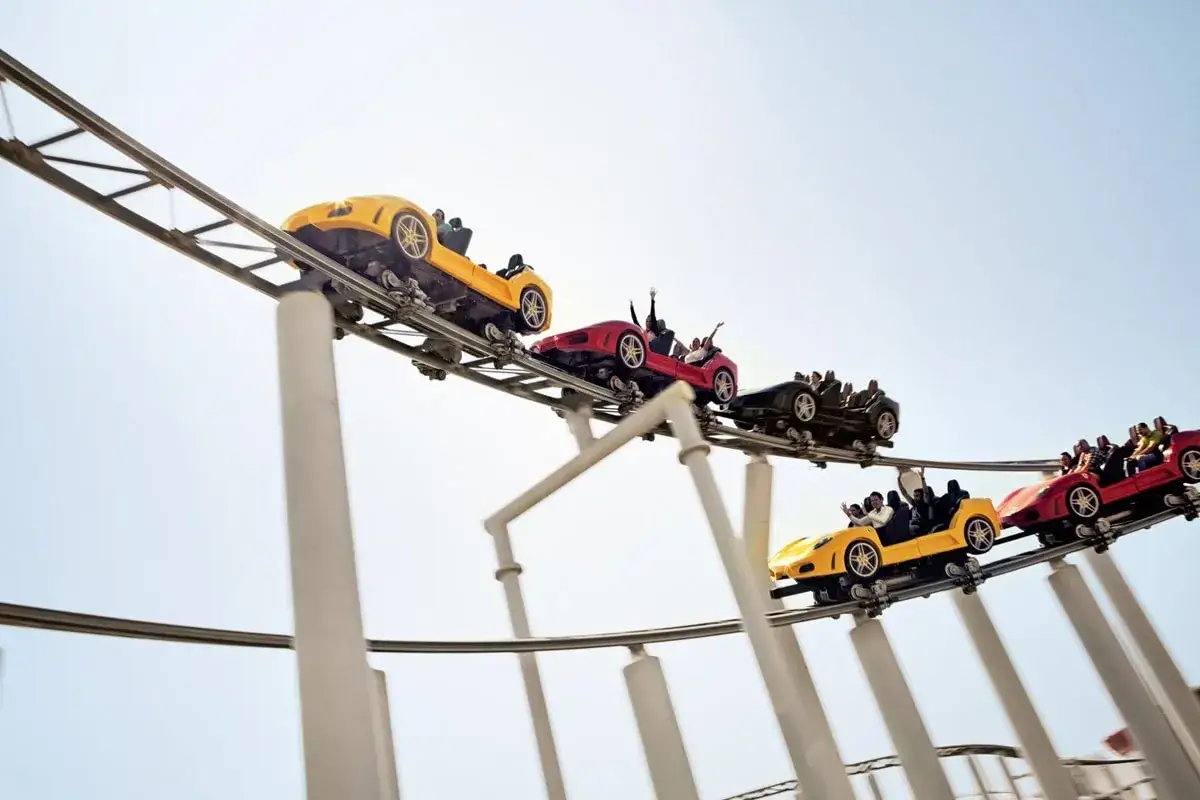 Kolejka górska w kształcie Ferrari na torach w Dubaju. Pasażerowie krzyczą z radości podczas szybkiej jazdy w Ferrari World.