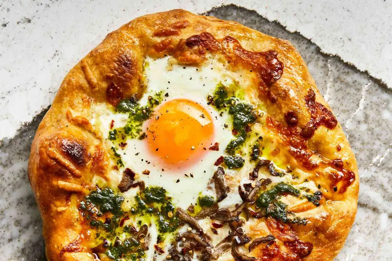 Apetyczna pizza z jajkiem na wierzchu, z zielonym sosem i grzybami. Idealna na śniadanie lub brunch.