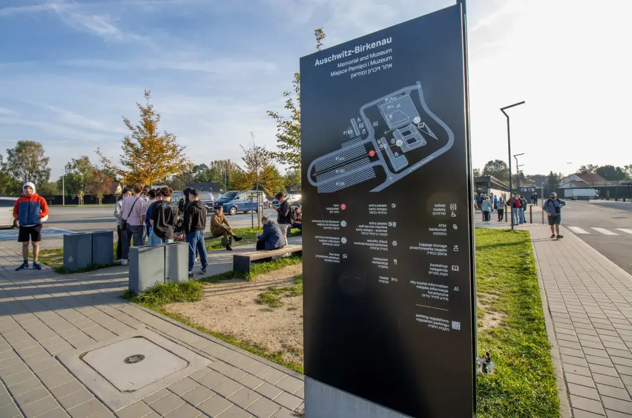 Grupo de turistas esperando cerca de un cartel informativo del Memorial de Auschwitz-Birkenau, tras llegar en autobús desde Cracovia.