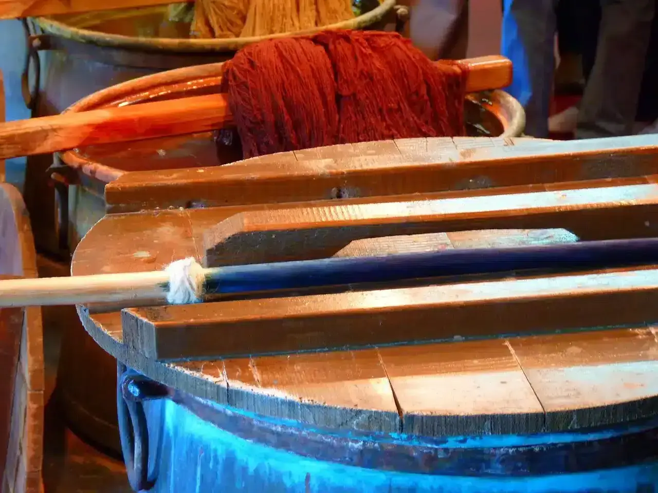 Cuve en bois pour l'ennoblissement textile, avec des b&acirc;tons et une pelote de fil rouge.