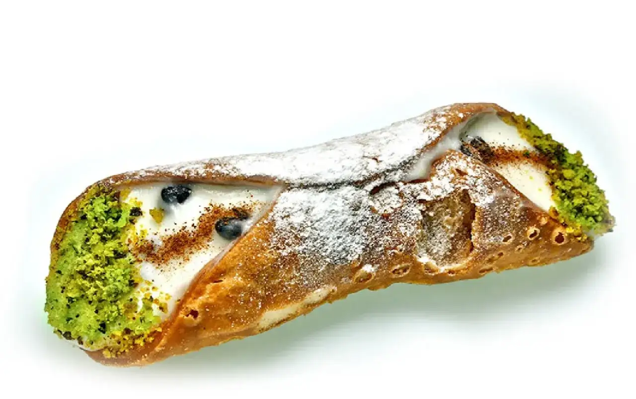 Un cannolo sicilien garni de cr&egrave;me, pistaches concass&eacute;es, myrtilles et saupoudr&eacute; de sucre glace.