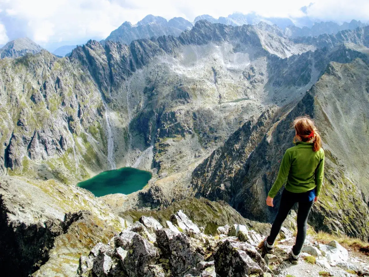Widok na narodową górę Słowaków, Tatry. Kobieta podziwia skaliste szczyty i turkusowe jezioro.