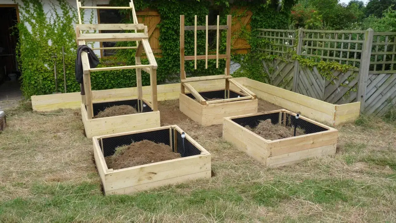 Un nouveau modèle de jardin potager en bois, prêt à être planté. Des bacs surélevés avec des structures pour soutenir les plantes grimpantes.