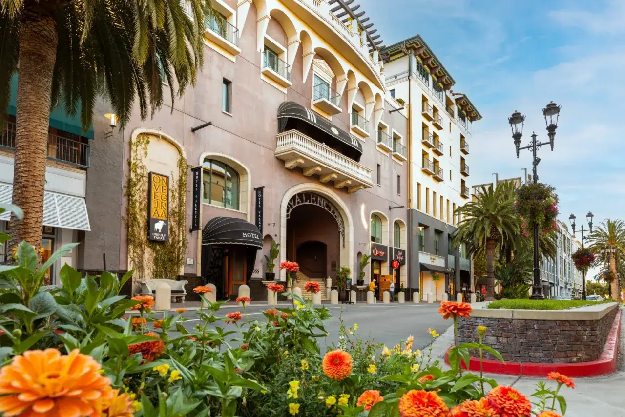 Blommor i f&ouml;rgrunden framf&ouml;r Hotel Valencia i San Jose, Costa Rica. En vacker dag med palmer och arkitektur.