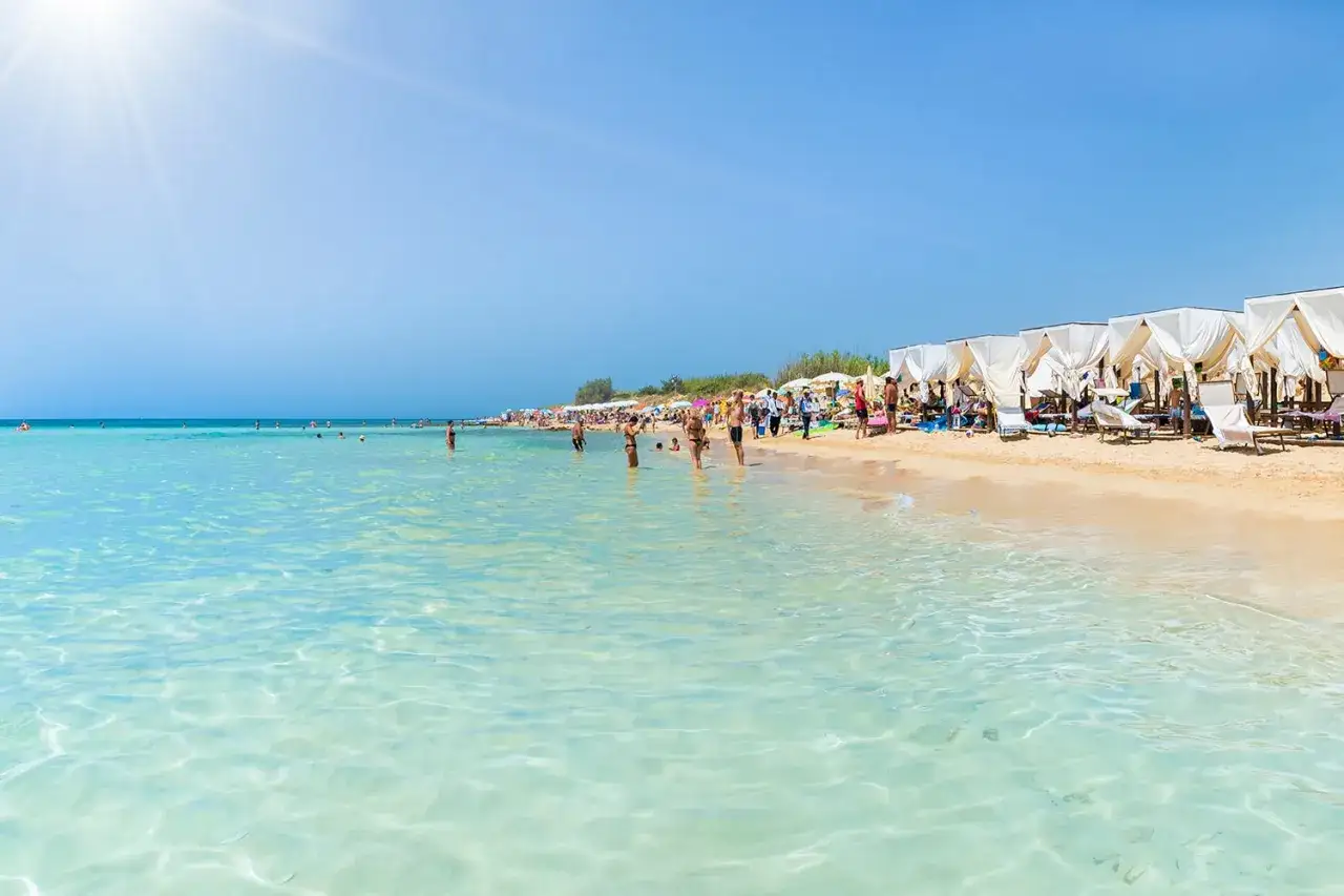 Spiaggia con acque cristalline e cabine bianche, ideale come localit&agrave; mare Puglia per famiglie.