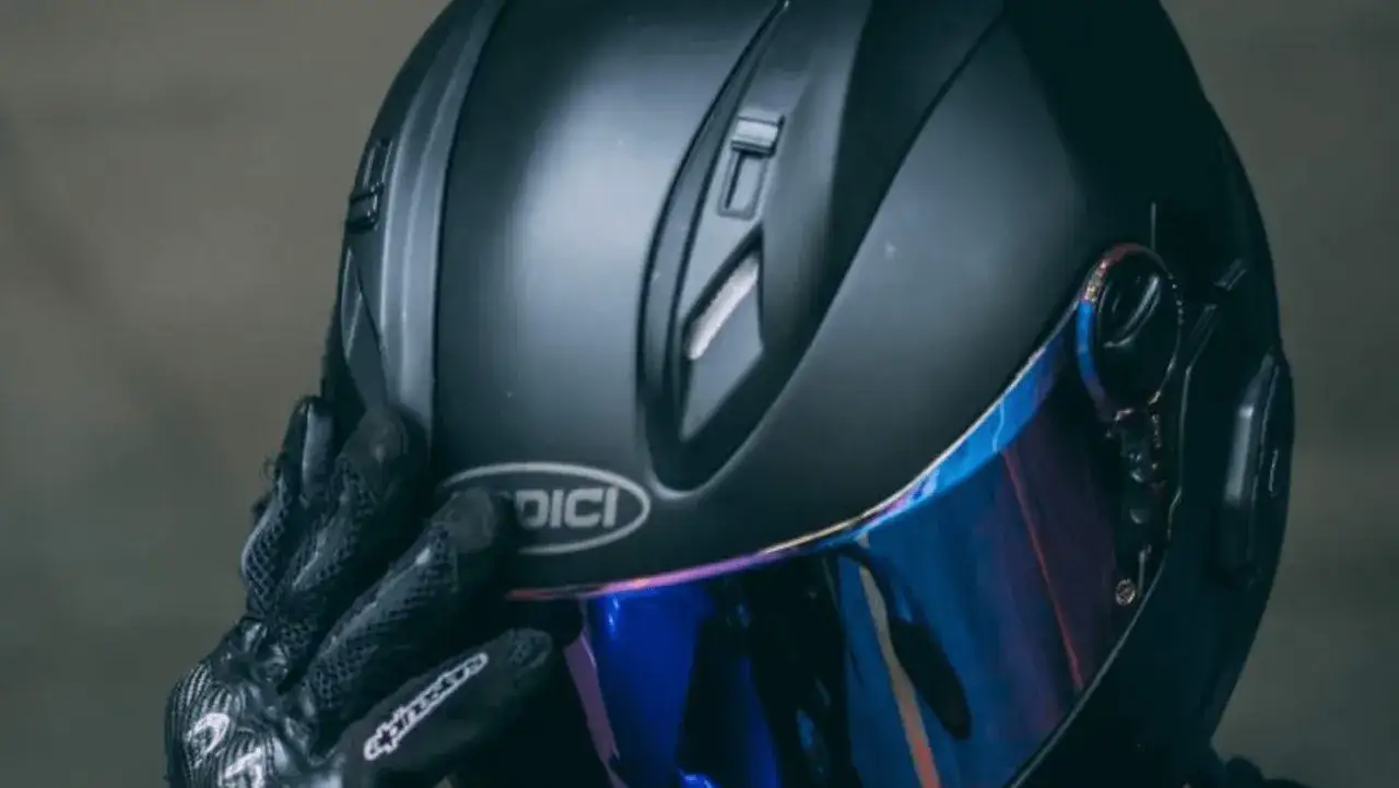 Casco moto 125 negro mate con visera iridiscente, listo para la aventura. Guantes de cuero negro completan el look.