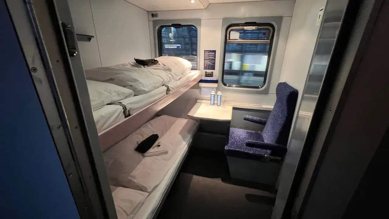 Sovkupé på ett euronight train med två bäddar, en stol och fönster med utsikt över natten.