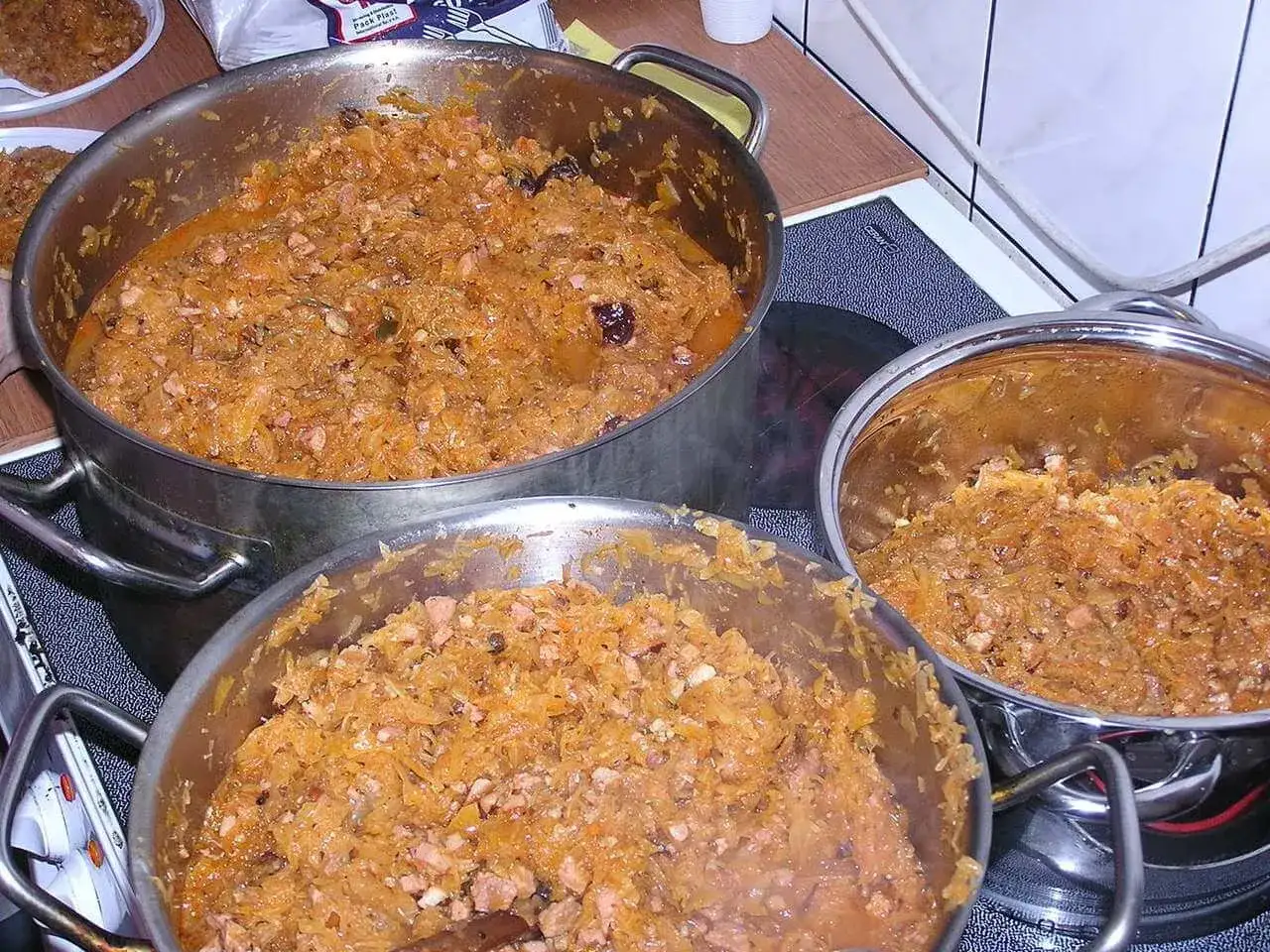 Wielkie garnki bigosu, gotowe do wekowania w piekarniku. Aromatyczne danie czeka na pasteryzację.