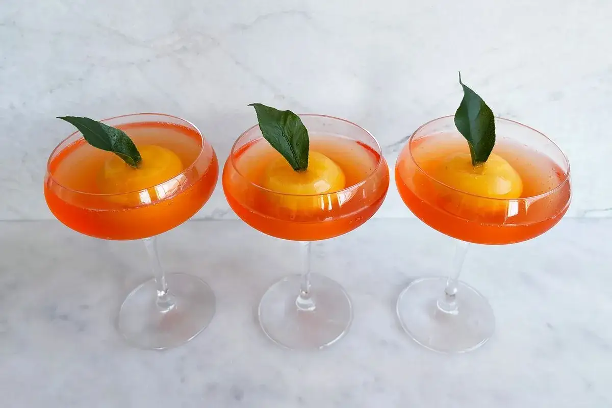 Trzy drinki Aperol w kieliszkach, każdy z pomarańczą i listkiem. Idealne na letnie popołudnie.