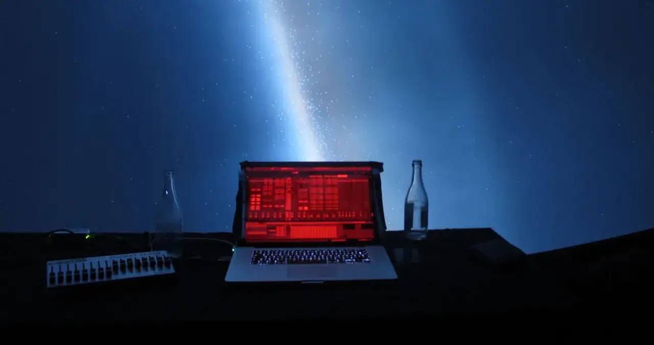Laptop z czerwonym ekranem, kontroler, butelki i rozgwieżdżone niebo. Idealne do **koncertów online**.