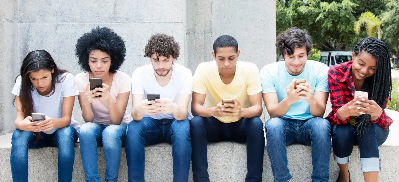 Six jeunes, dont certains semblent avoir 13 ans, sont absorb&eacute;s par leurs smartphones. Le temps d'&eacute;cran recommand&eacute; pour cet &acirc;ge est &agrave; surveiller.