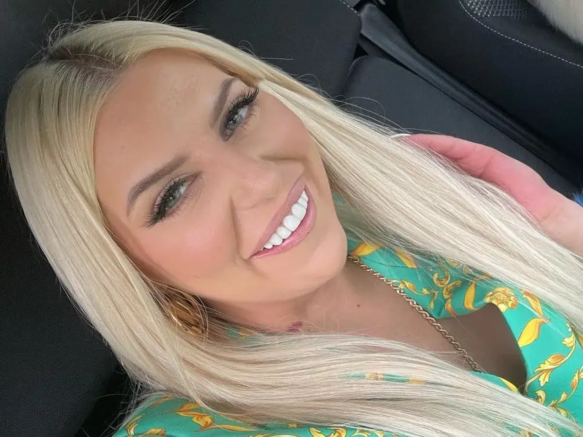 Uśmiechnięta Julia von Stein w zielonej sukience z złotym wzorem, z długimi blond włosami i makijażem.