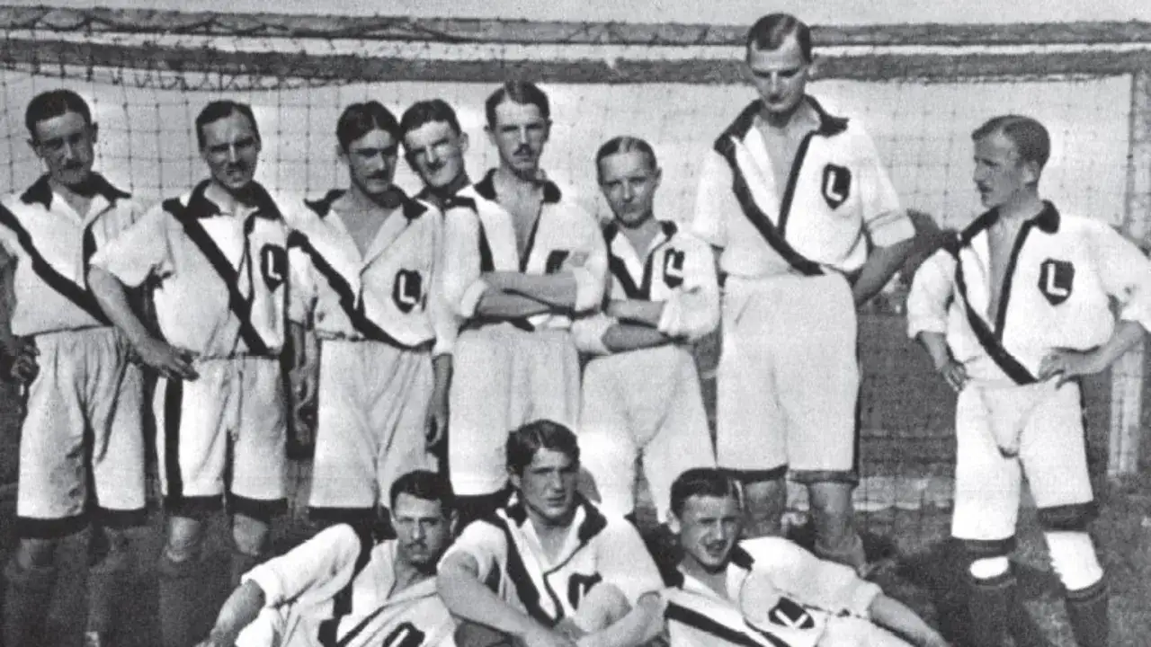 Byli piłkarze Legii w historycznych strojach, pozują do zdjęcia drużynowego.