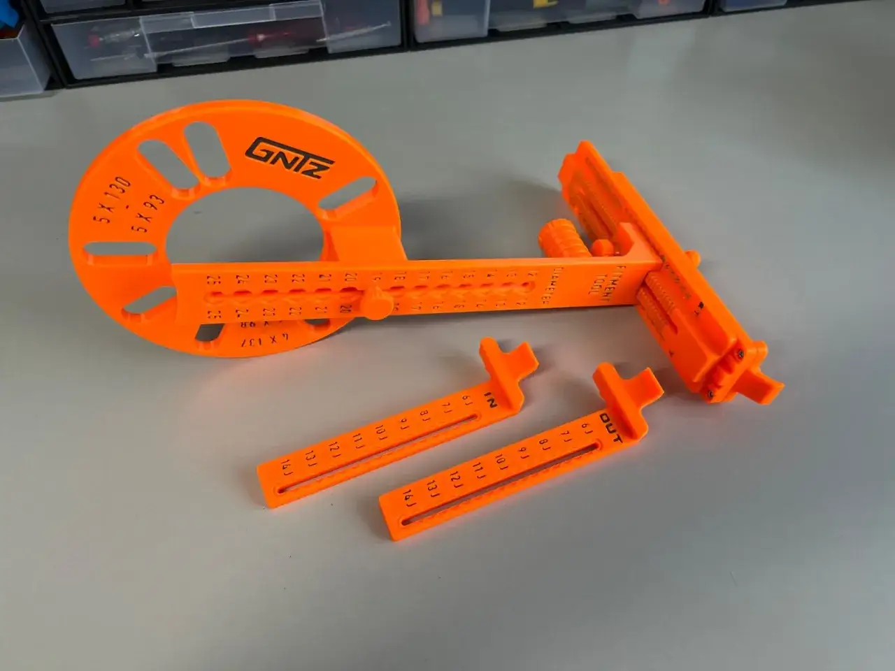 Ein orangefarbenes Werkzeug hilft beim felgenbreite messen. Es hat Skalen und zwei zusätzliche Messschieber.