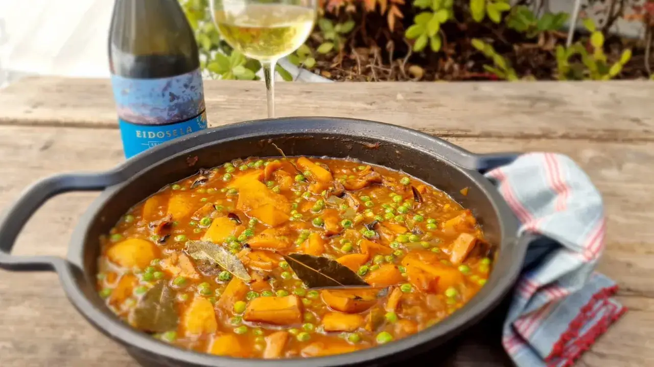 Un guiso casero de papas con choco, guisantes y laurel, acompa&ntilde;ado de vino blanco.