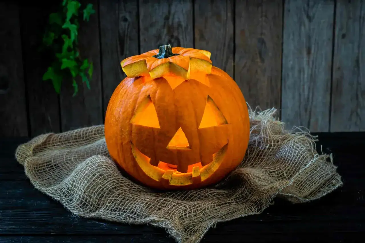Zucca di Halloween intagliata, illuminata dall'interno, su tela grezza. Un classico 
