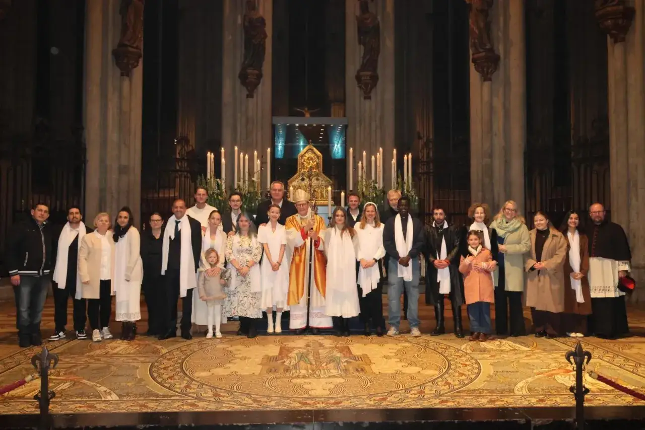 Gruppe von Menschen, darunter Kinder und Erwachsene, posiert mit einem Bischof in einer Kirche. Die Frage