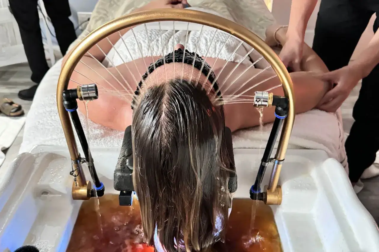 Eine Frau l&auml;sst sich die **Haare nur mit Wasser waschen** in einer speziellen Vorrichtung, die Wasserstrahlen auf ihren Kopf richtet.