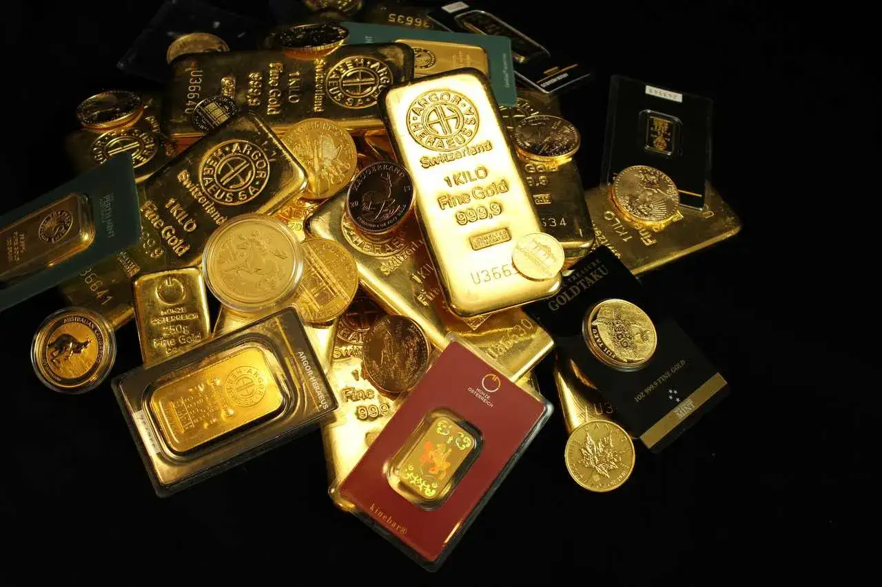 Złote sztabki i monety, w tym 1-kilogramowa sztabka, pokazują, ile waży sztabka złota.
