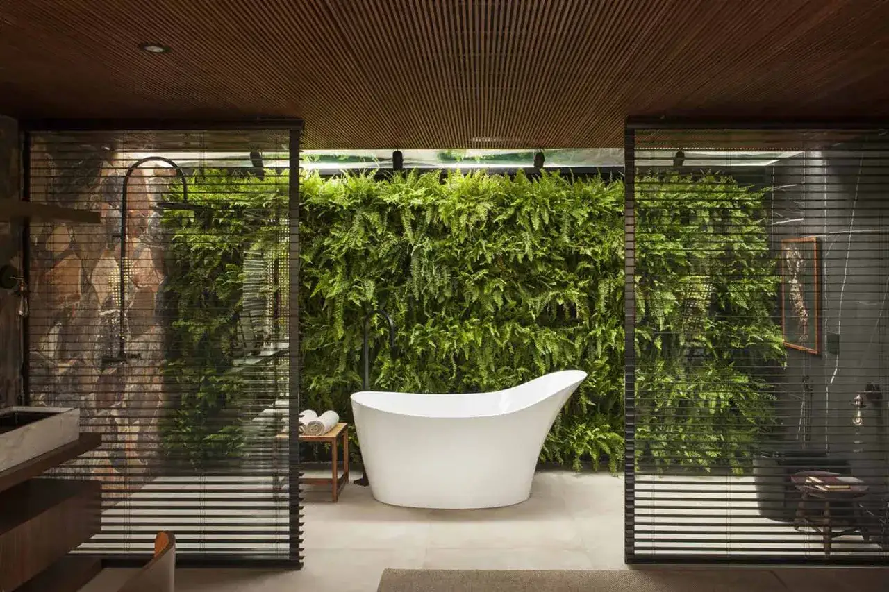 Bagno di lusso con vasca freestanding e parete verde rigogliosa. Idee bagno originali per un'oasi di relax.