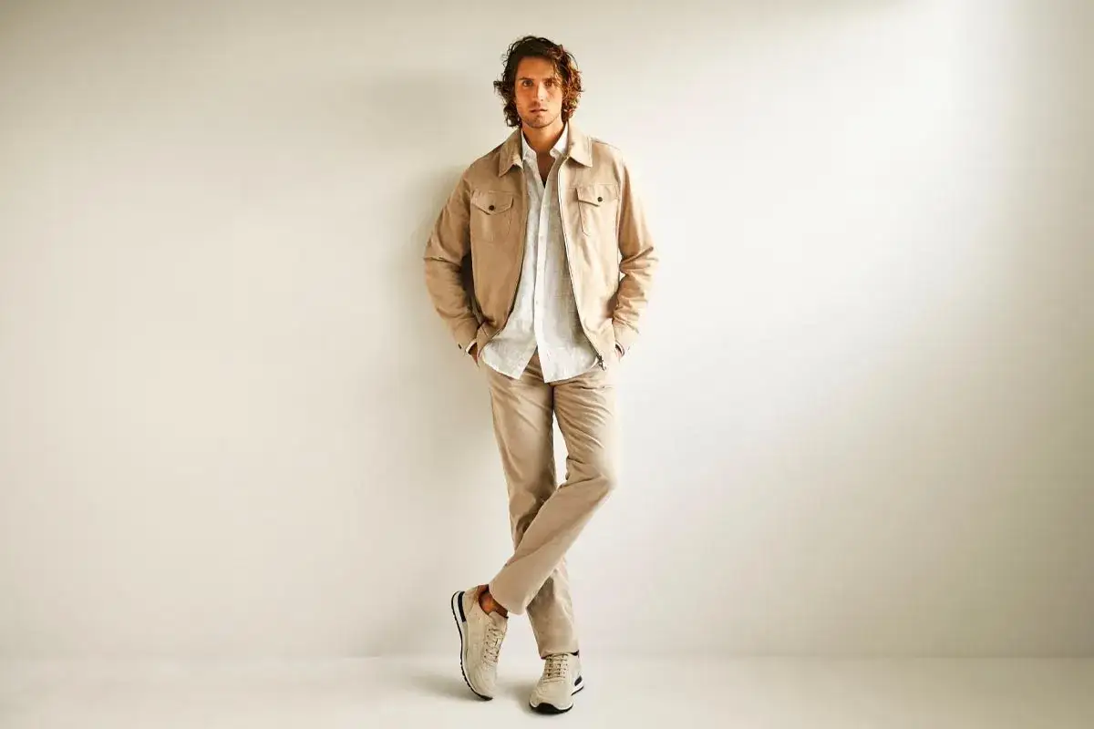 Hombre con estilo business casual, viste chaqueta beige, camisa blanca y pantalones a juego.
