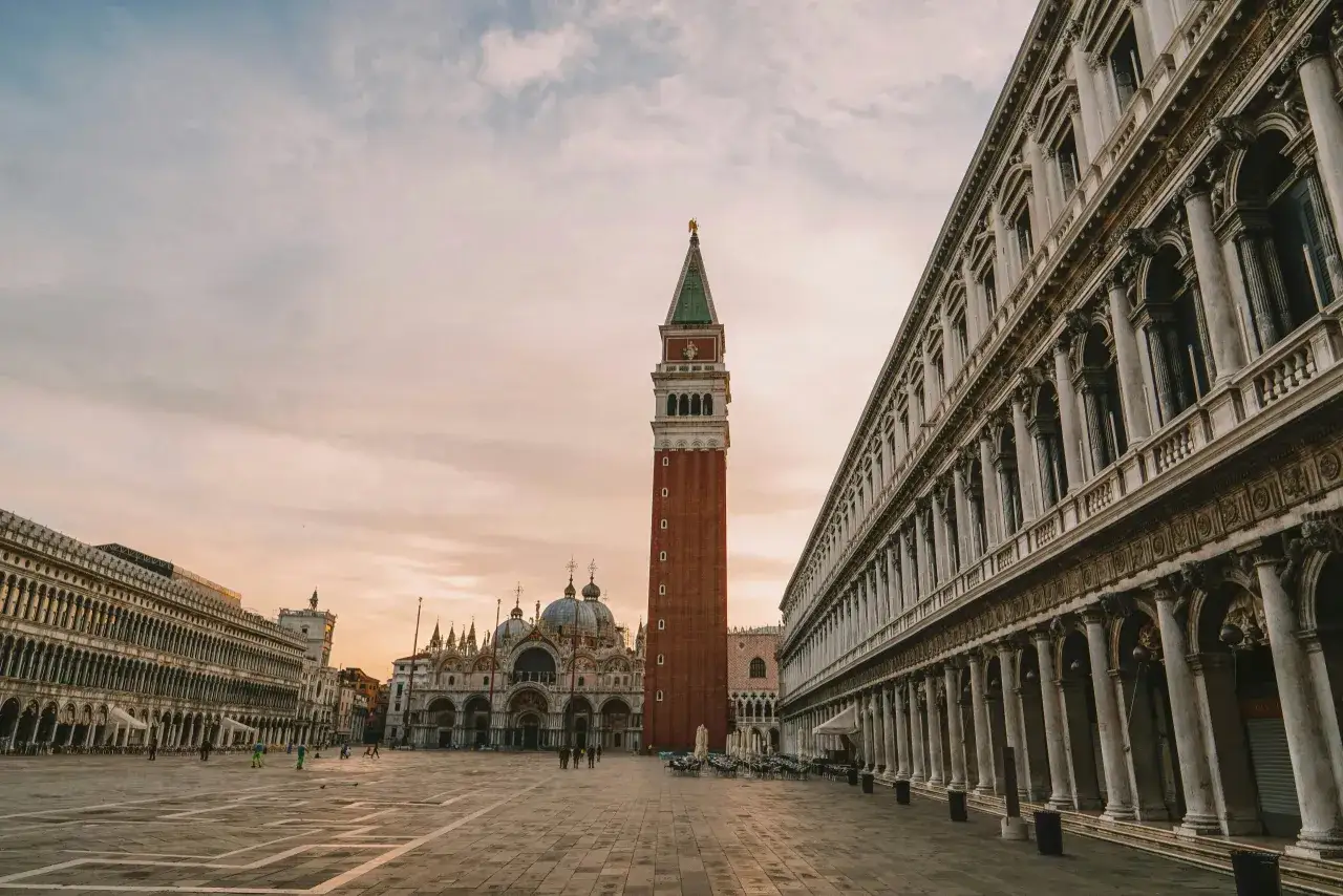 Alba a **Piazza San Marco Venezia**. La Basilica e il Campanile si stagliano contro il cielo rosato, con le Procuratie a destra.