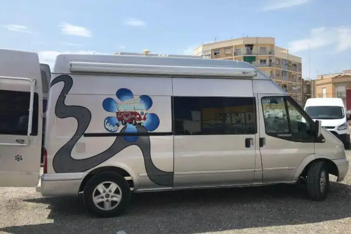 Furgoneta camperizada con motor Ford 2.2 TDCI 140 CV, decorada con un diseño de carretera y una flor con una furgoneta retro.