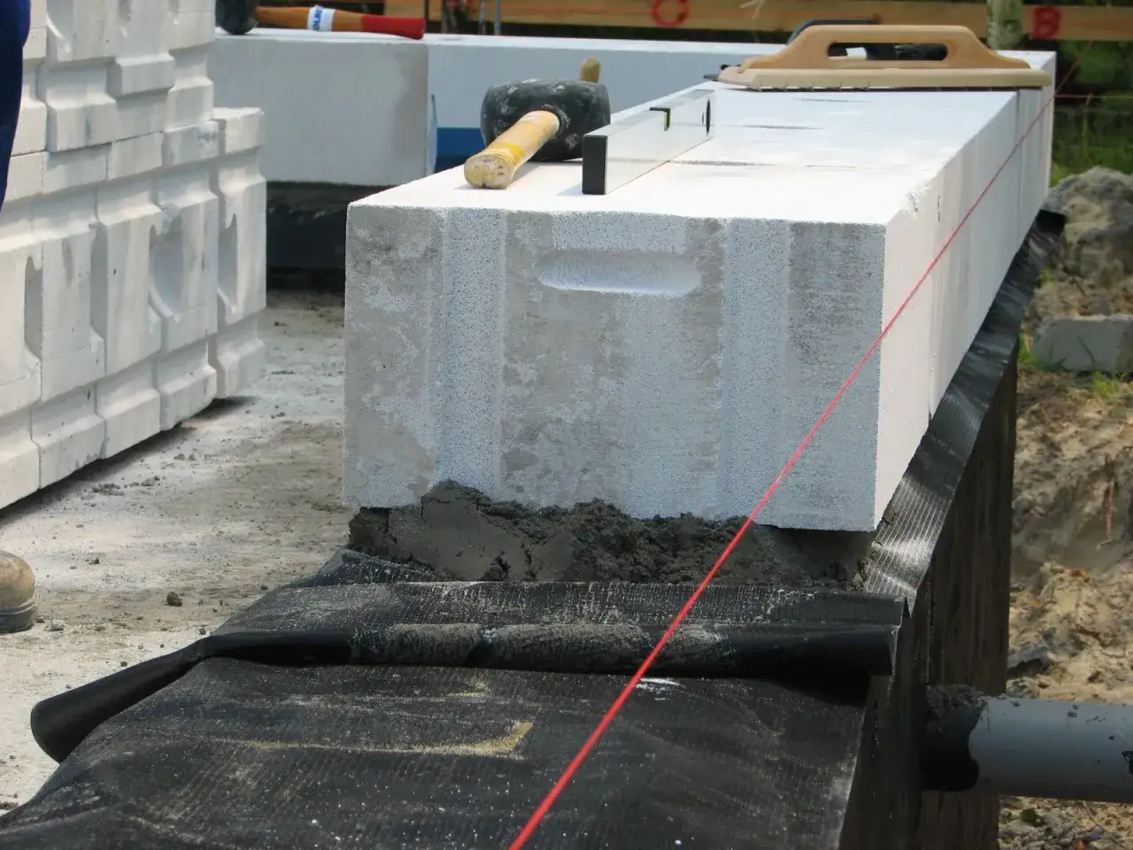 Ściana fundamentowa z bloczków betonowych wznoszona z precyzją, z użyciem poziomicy i sznurka.