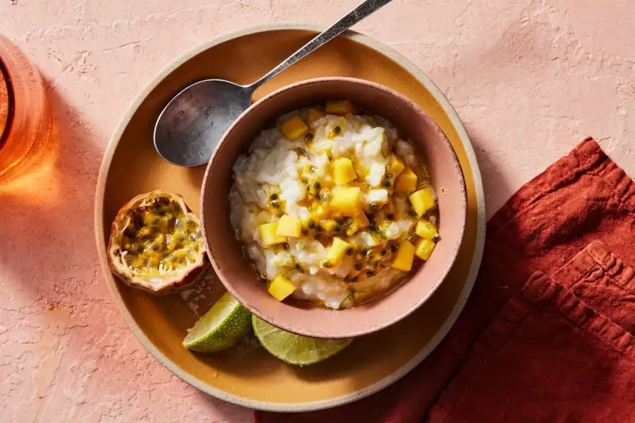Un déliceux dessert lait de coco crémeux, garni de mangue et de fruits de la passion, servi avec des quartiers de citron vert.