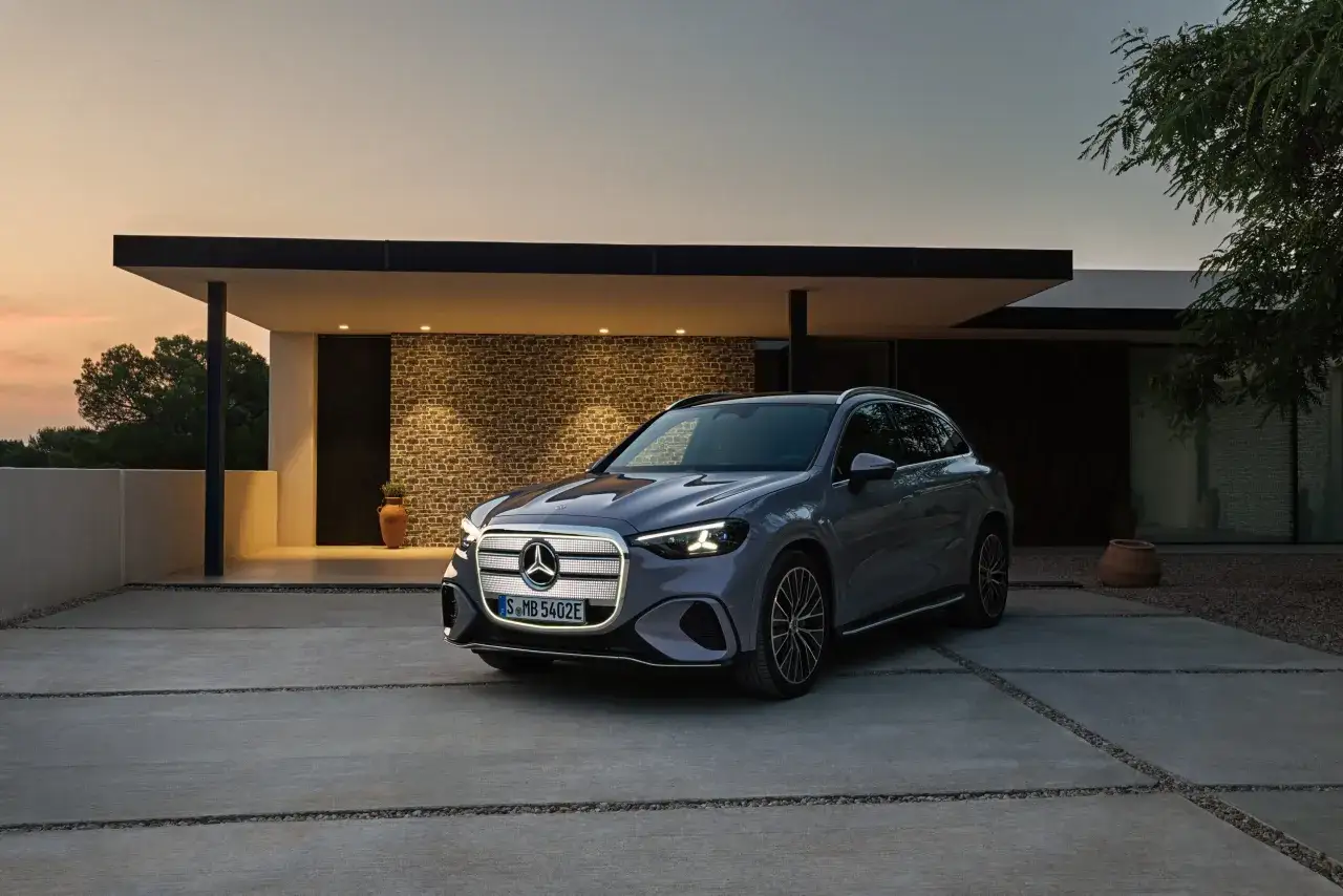Elegancki Mercedes EQC stoi przed nowoczesnym domem o zachodzie słońca.