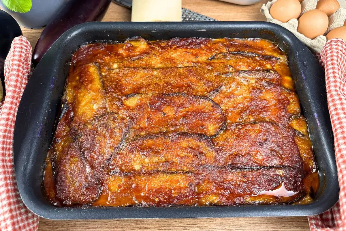 Una teglia fumante di parmigiana di melanzane napoletana, con strati dorati e succulenti, pronta per essere gustata.