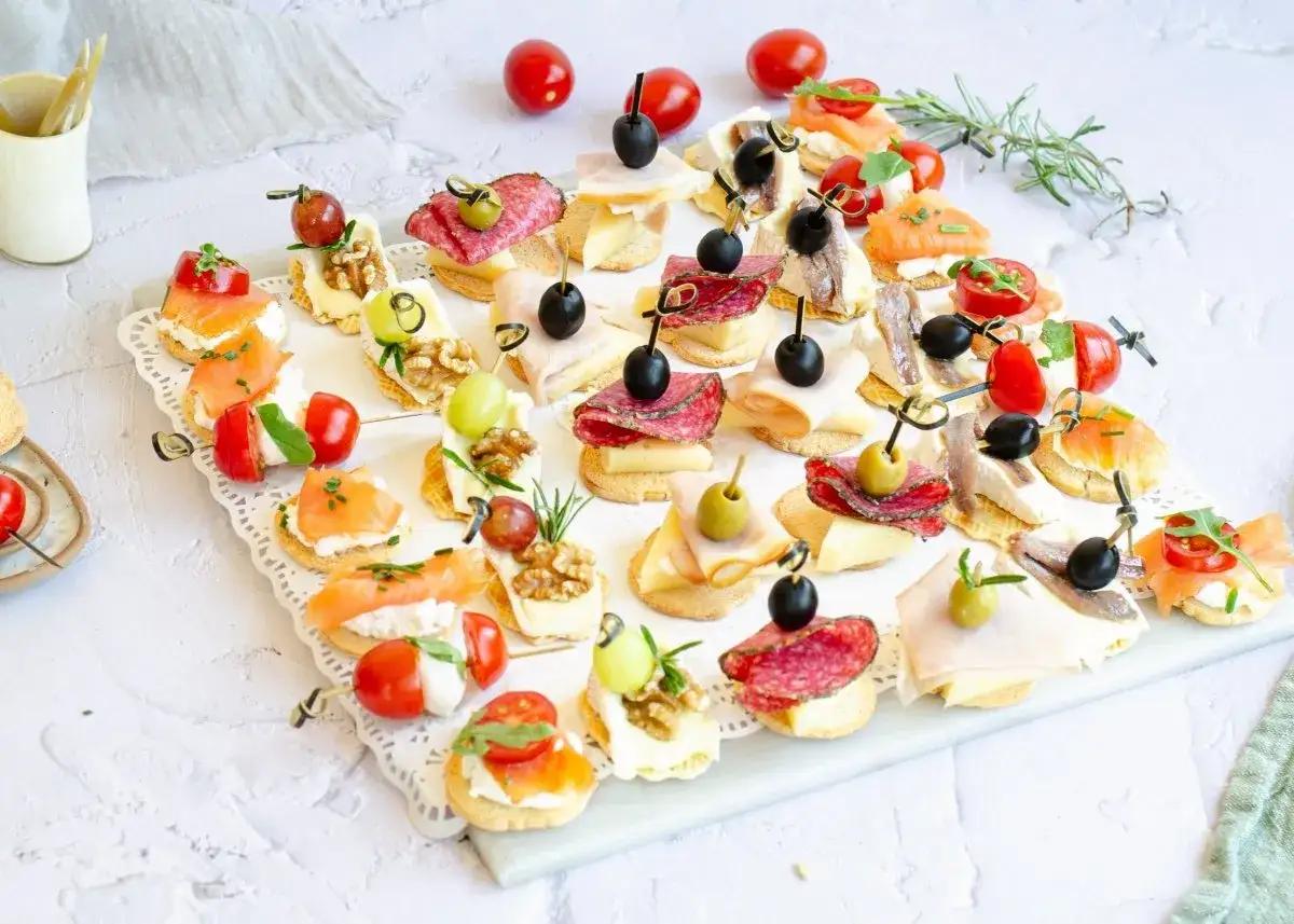Delicioso surtido de crostini italiano con salmón, salami, aceitunas, queso y tomates.