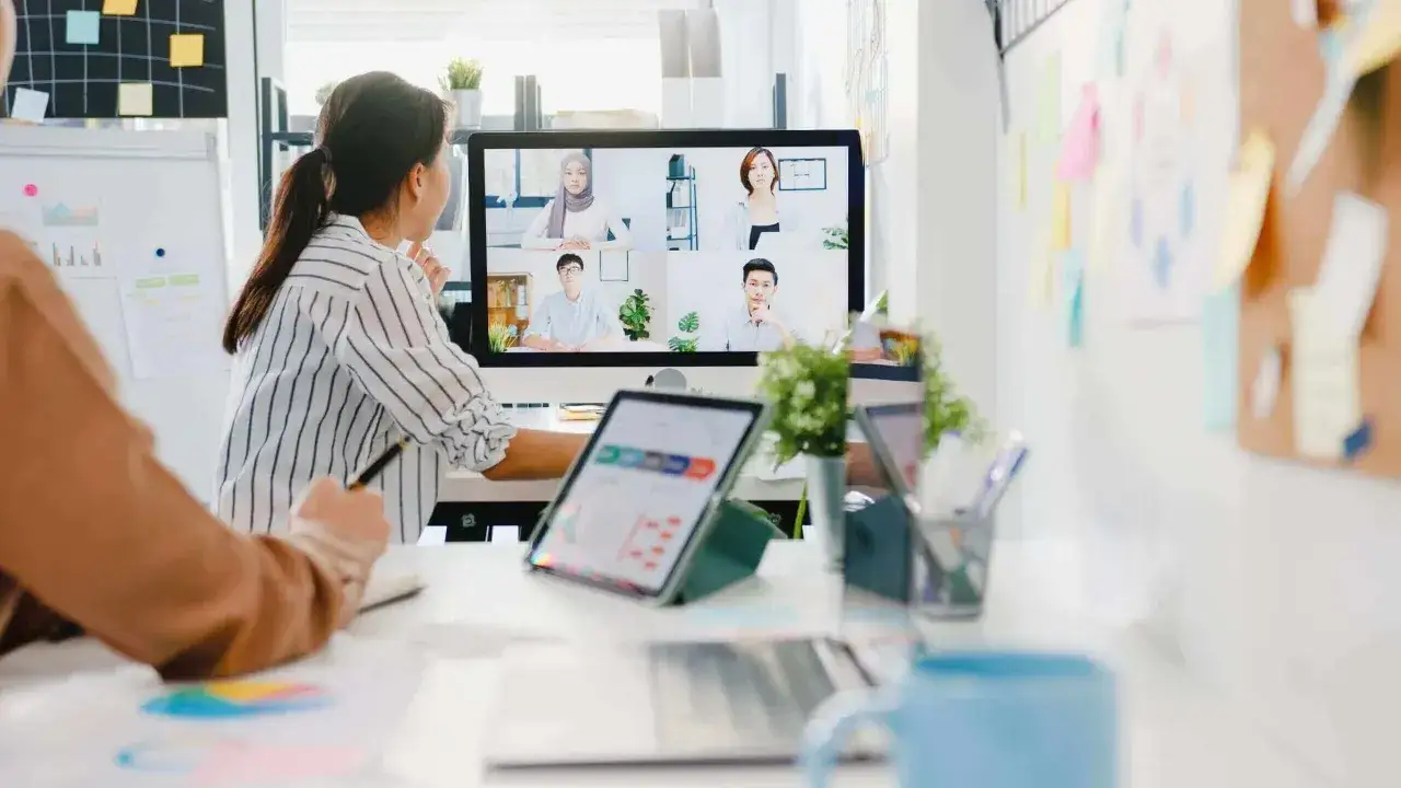 Mujeres colaborando en una reuni&oacute;n virtual. La pantalla muestra a varios miembros de equipos virtuales en una videollamada.