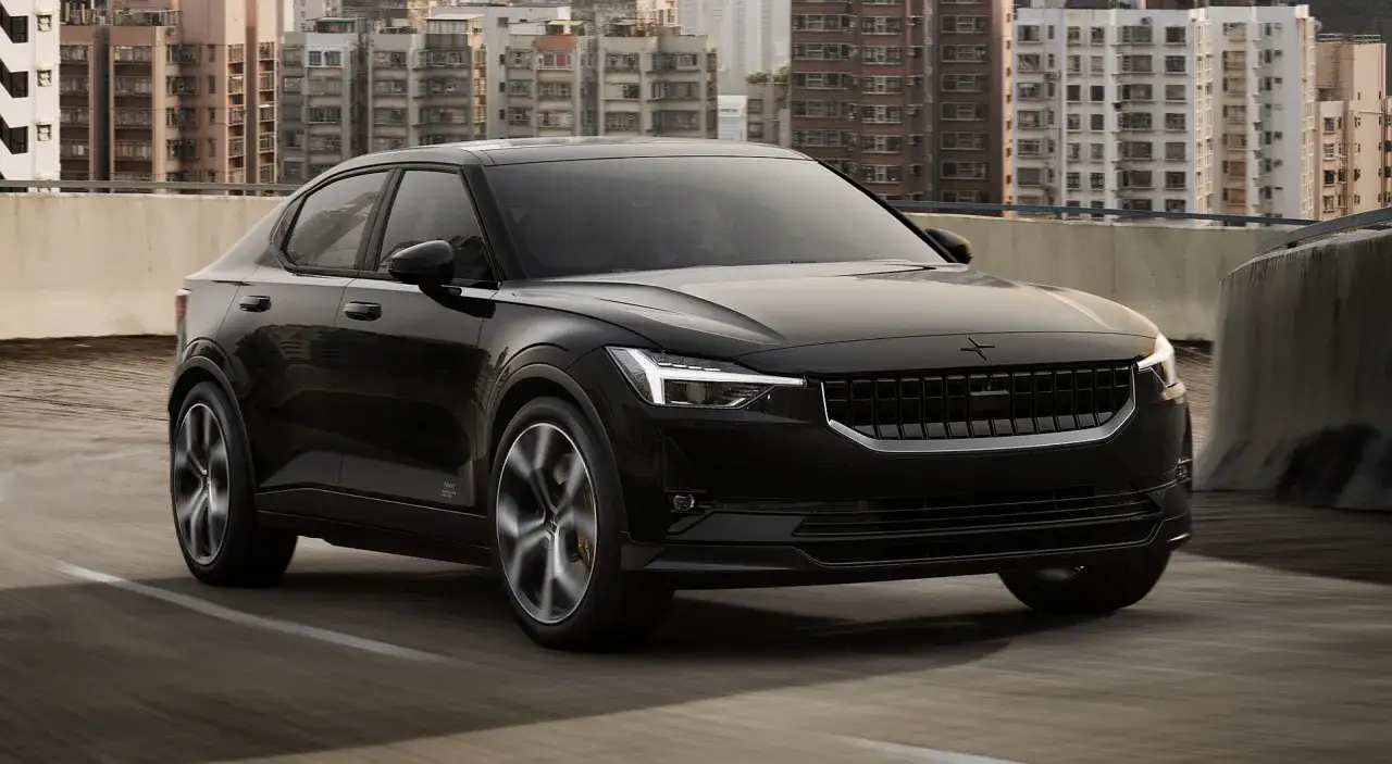 Czarny Polestar 2 pędzi po moście, mijając miejską panoramę.