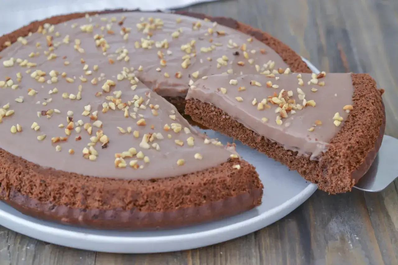 Una golosa crostata al cioccolato con una crema vellutata e granella di nocciole, una fetta è appena stata servita.