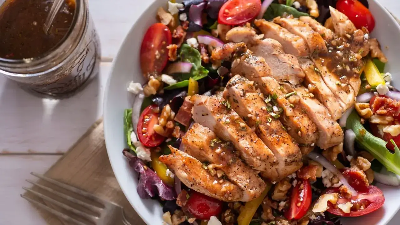 Deliciosa ensalada saludable con pollo a la parrilla, tomates, nueces y aderezo.
