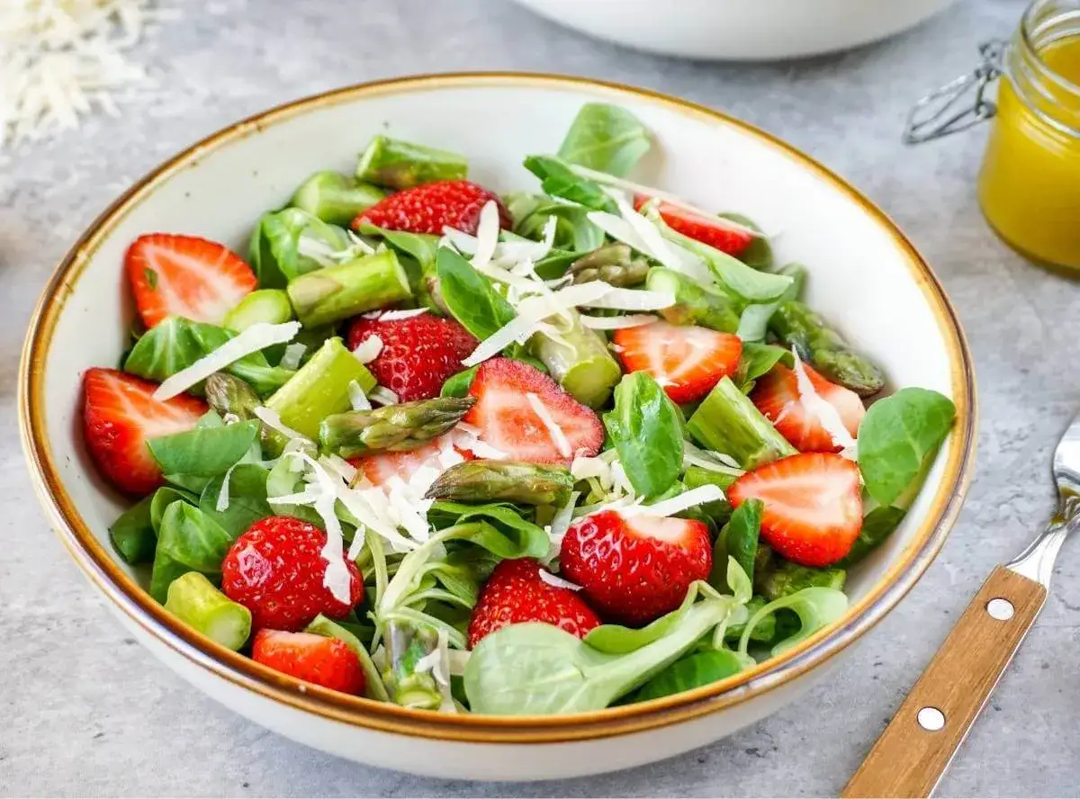 Frischer Spargelsalat mit Erdbeeren, garniert mit Parmesan. Ein leichter Genuss für warme Tage.