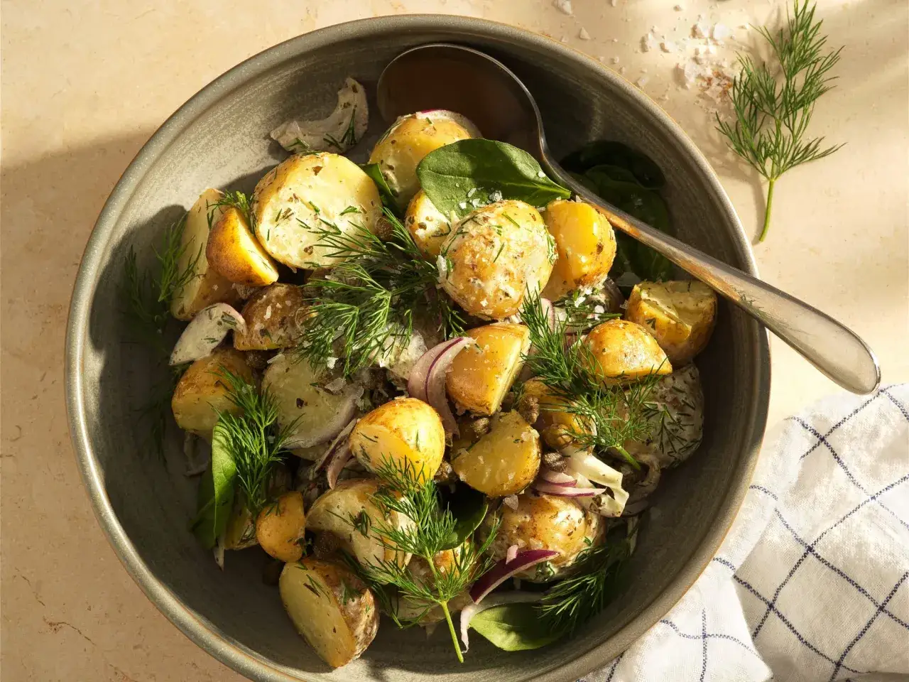 En skål med krämig smashed potatis, garnerad med dill och rödlök. Perfekt sommarbuffé!