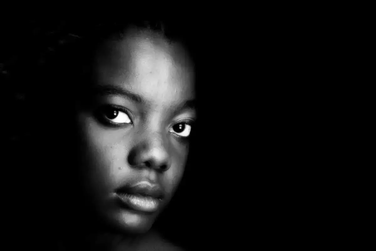 Un intenso ritratto bianco e nero di una giovane ragazza, con lo sguardo diretto verso l'osservatore.