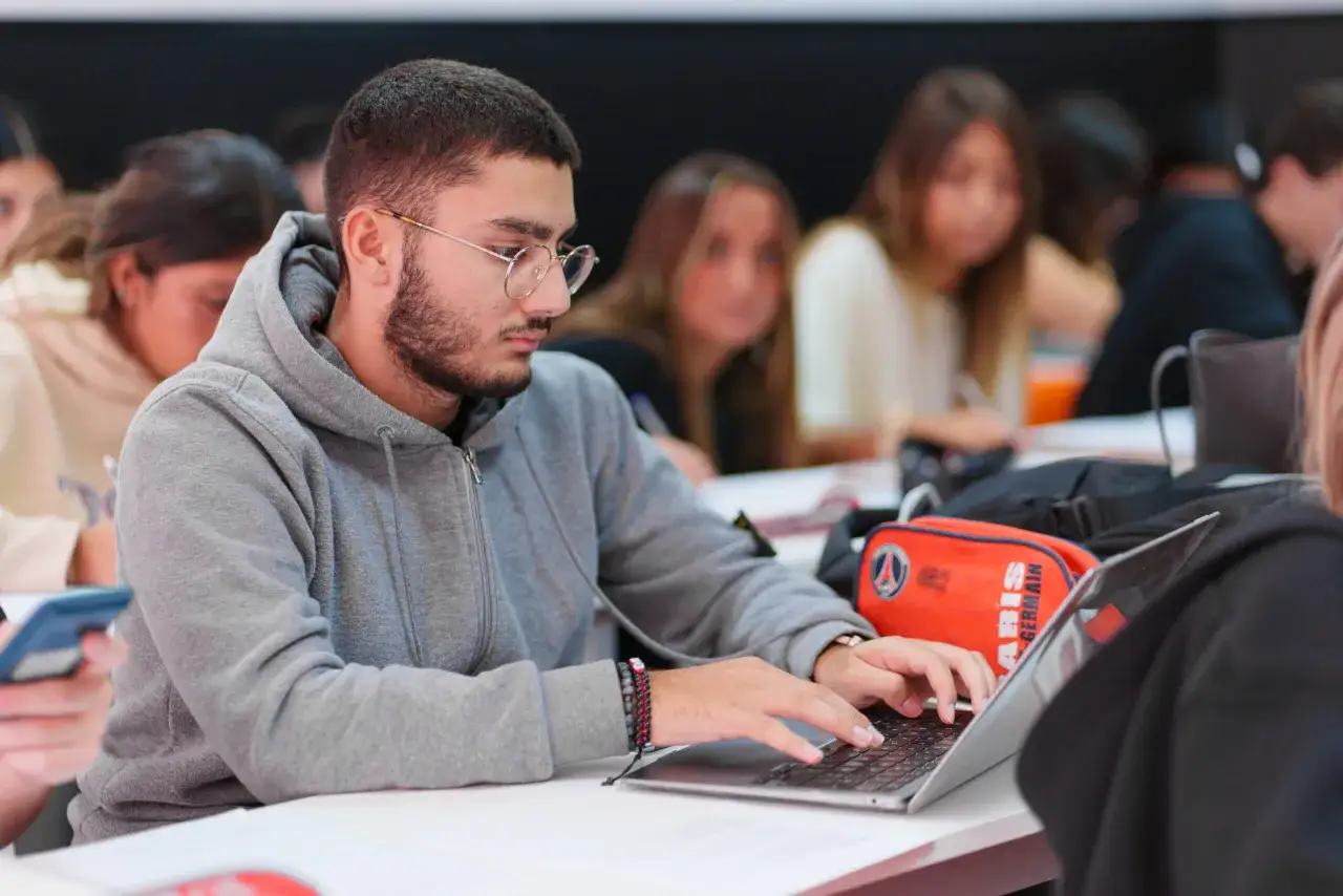 Un &eacute;tudiant en BTS Audioproth&eacute;siste en alternance travaille sur son ordinateur portable, concentr&eacute; sur ses &eacute;tudes.