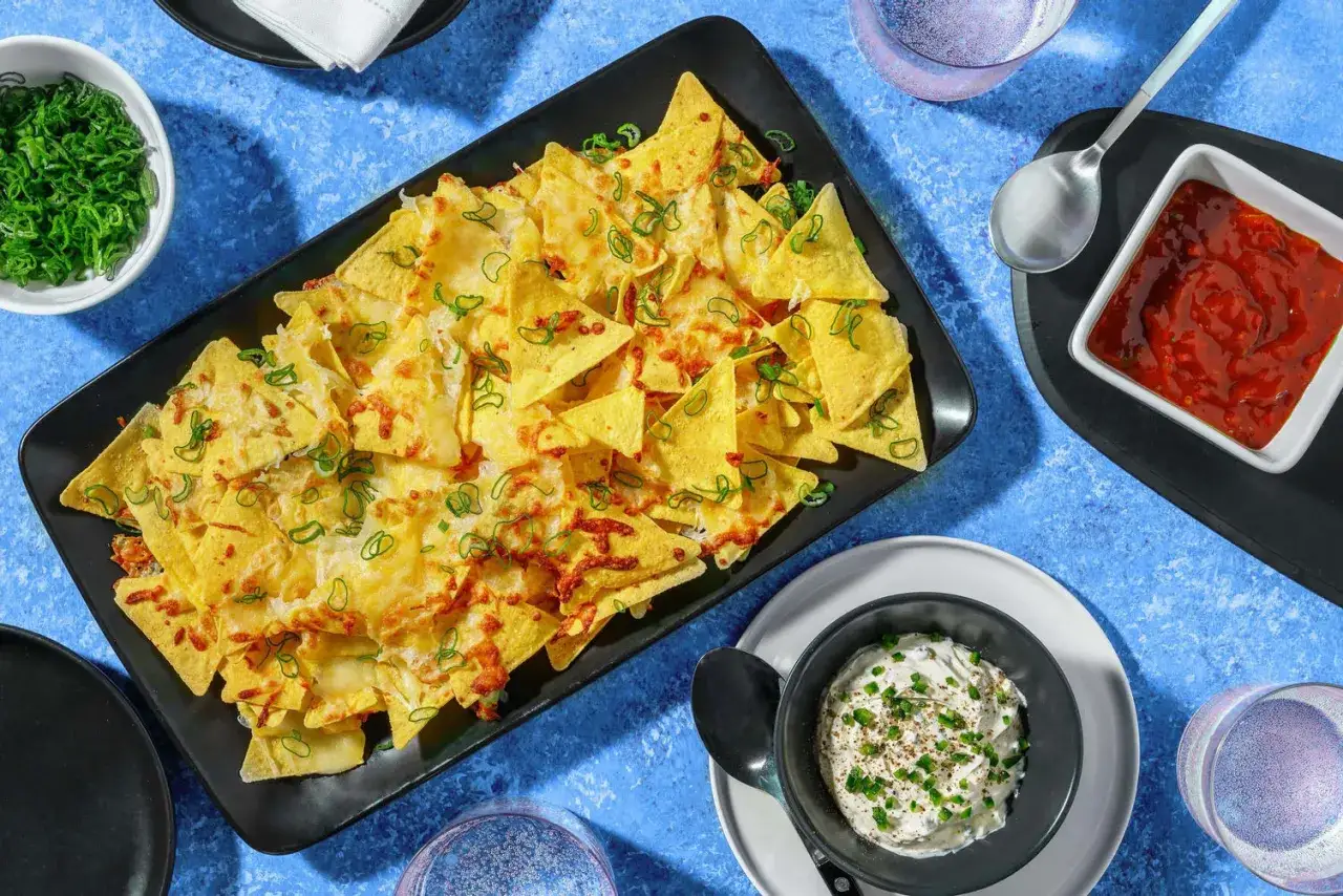 H&auml;rliga nachos i ugn med sm&auml;lt ost och salladsl&ouml;k, serverade med salsa och gr&auml;ddfil. Perfekt f&ouml;r en mysig kv&auml;ll!
