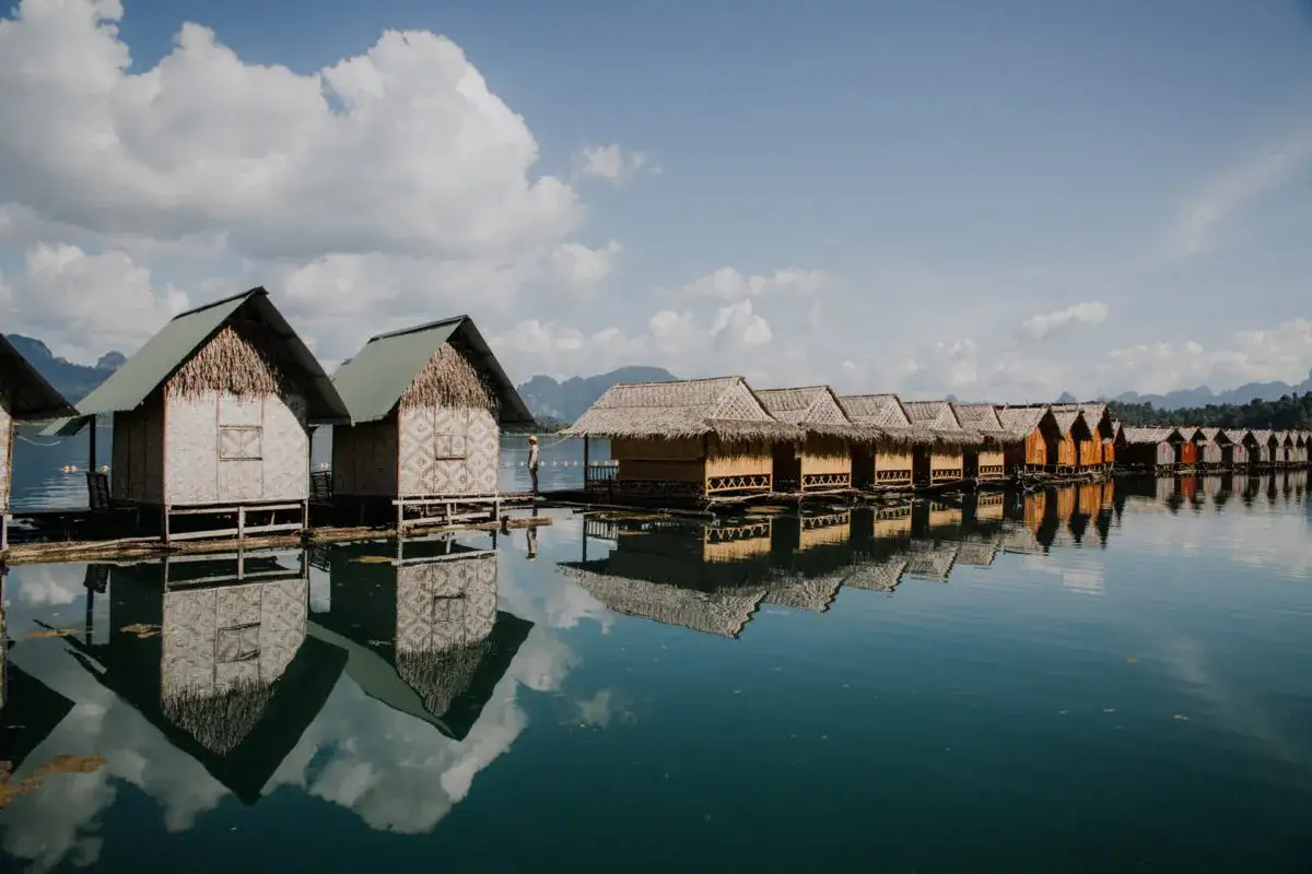 Urocze, drewniane chatki na wodzie w Khao Sok, Tajlandia, odbijają się w spokojnej tafli jeziora.