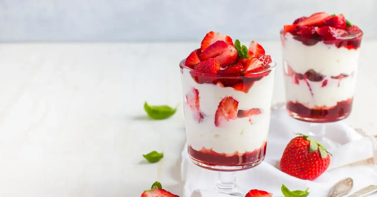 Deliciosos postres en copas con capas de crema blanca y fresas frescas, coronados con más fresas. Un placer visual y gustativo de fresas con leche condensada.
